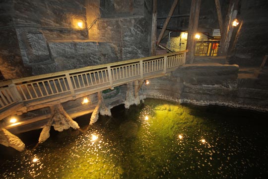 puente de madera sobre un estanco subterráneo, iluminados con luz artificial