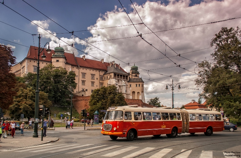 Un autobús de color rojo, probablemente de los años cincuenta del siglo pasado, con una de las fachadas del Castillo de Wawel en segundo plano