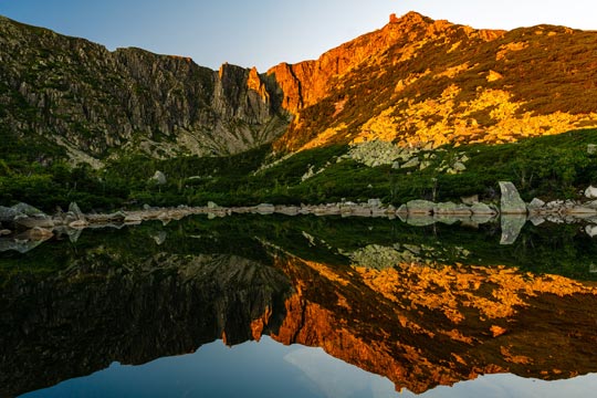 Puesta de sol en un lago que refleja las montañas que lo rodean