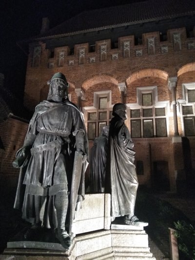 Esculturas de gran tamaño de caballeros de la edad media; en el fondo se divisa parte del castillo de ladrillo, vista nocturnade 