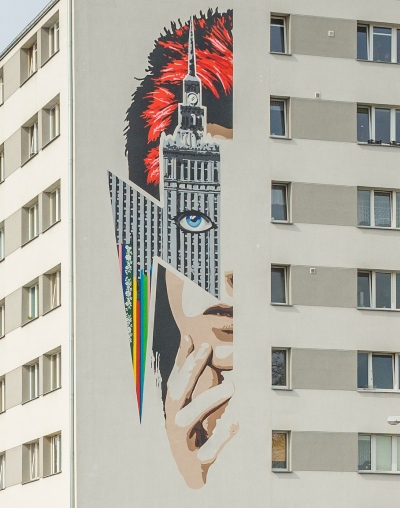 Mural en la fachada de un bloque de pisos, con la cara de David Bowie parcialmente cubierta con el antifaz que representa el Palacio de Cultura y Ciencia, uno de los más emblemáticos de Varsovia