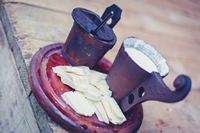 recipientes regionales de madera con bebida láctea parecida al kefir y trozos de queso fresco sobre una tabla de madera