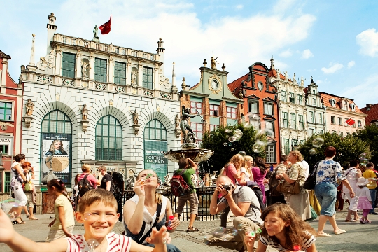 Niños y adultos haciendo pompas de jabón delante de un edificio histórico un día soleado de verano