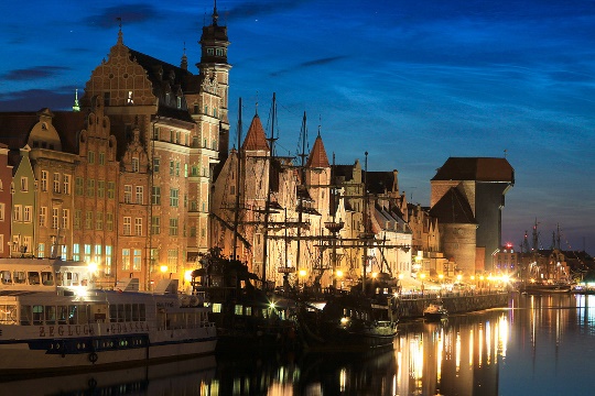 Panorama nocturna del antiguo muelle de Gdansk, con vasas del casco antiguo, la grúa medieval y barcos en el río