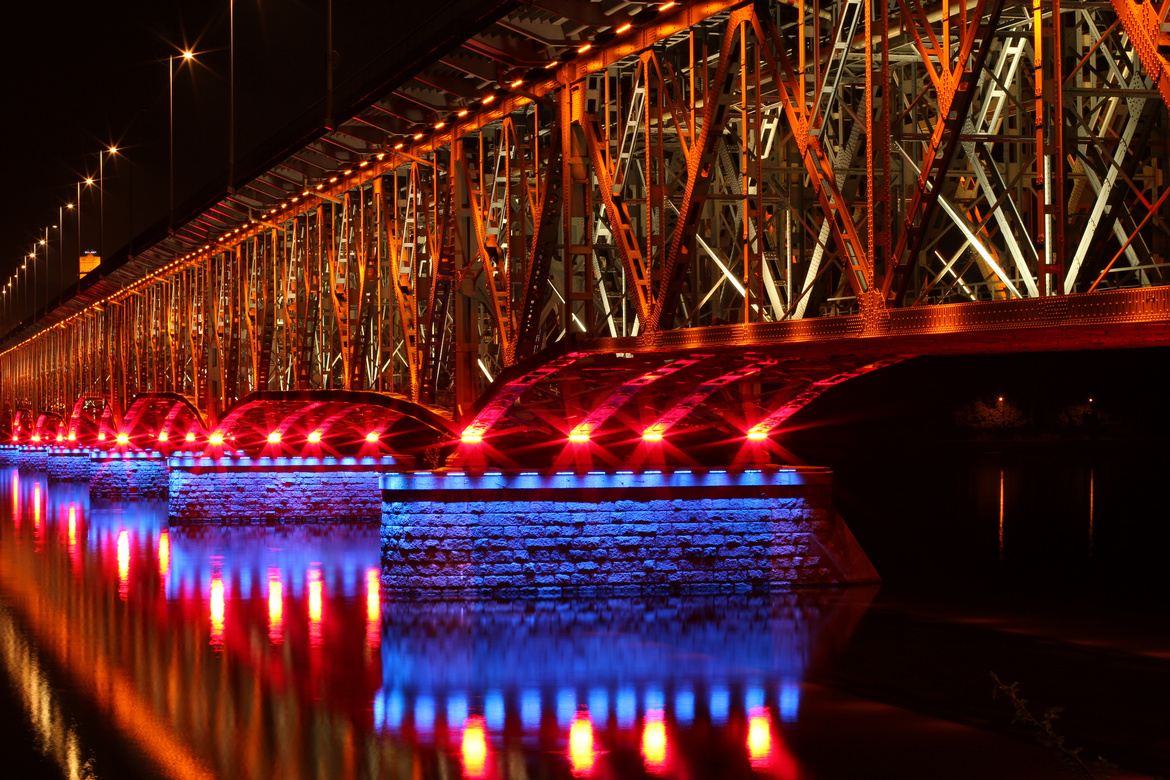 Un largo y alto puente atravesando el río. Foto nocturna