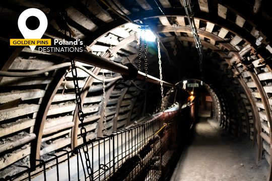 Túnel subterráneo asegurado con tablas de madera, y maquinaria típica de una mina de carbón