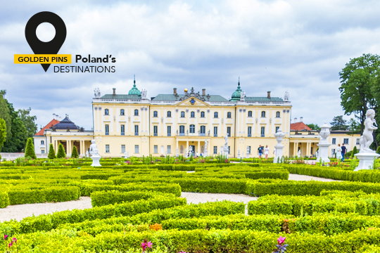 Fachada principal de un elegante palacio, con un parque de estilo francés delante