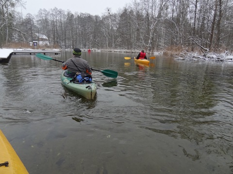 grupo de personas practicando kayak en un río, rodeado de un paisaje de invierno
