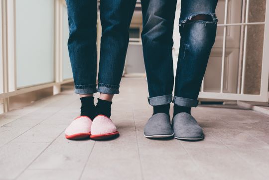 Se ven las piernas de dos personas en zapatillas de andar por casa