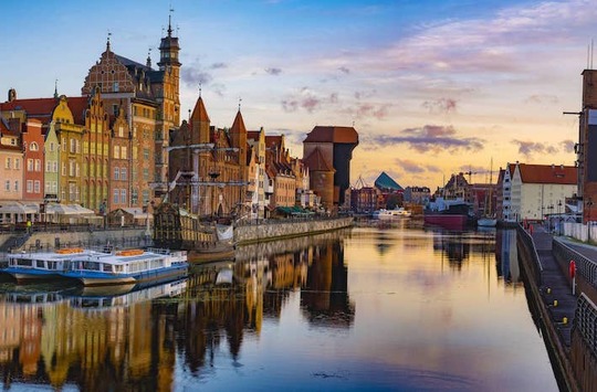 Foto che mostra degli edifici medievali che si specchiano su un fiume a Danzica