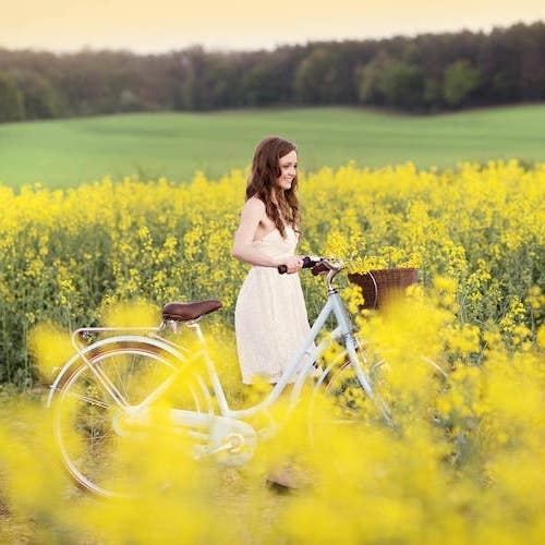 Ragazza con bici in un campo di colza