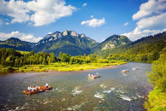 Persone in kayak su un fiume; sullo sfondo, una montagna