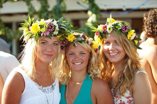 Tre ragazze sorridenti che portano le ghirlande di fiori, estate